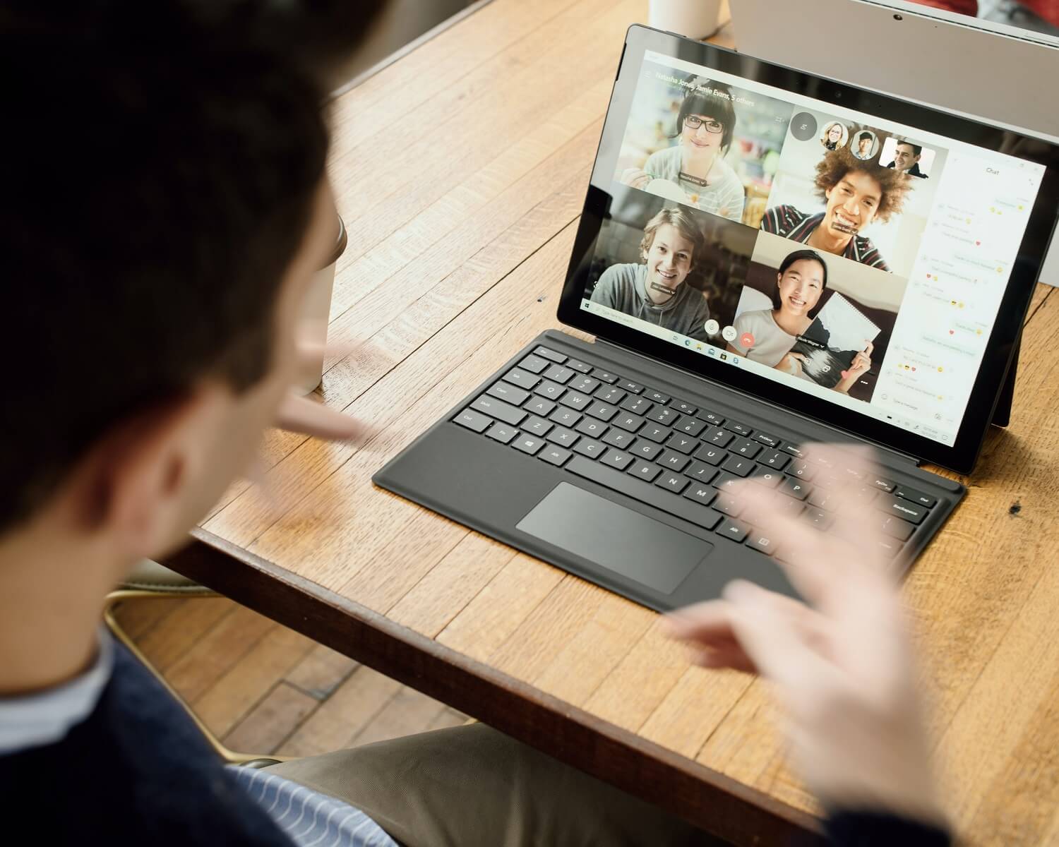 Ein Laptop auf einem Schreibtisch zeigt einen Split Screen während einer Videokonferenz mit 4 weiteren Teilnehmern.