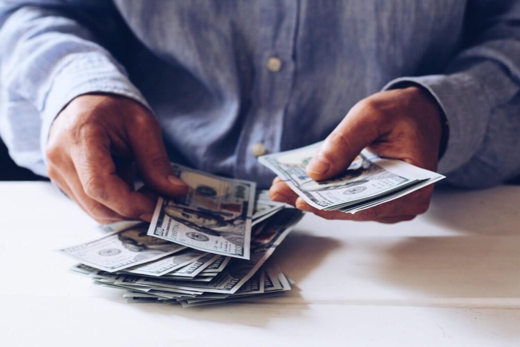 Mann zählt Geld, welches er mit der Monetarisierungsfunktion eines Podcast-Hosting-Anbieters eingenommen hat.