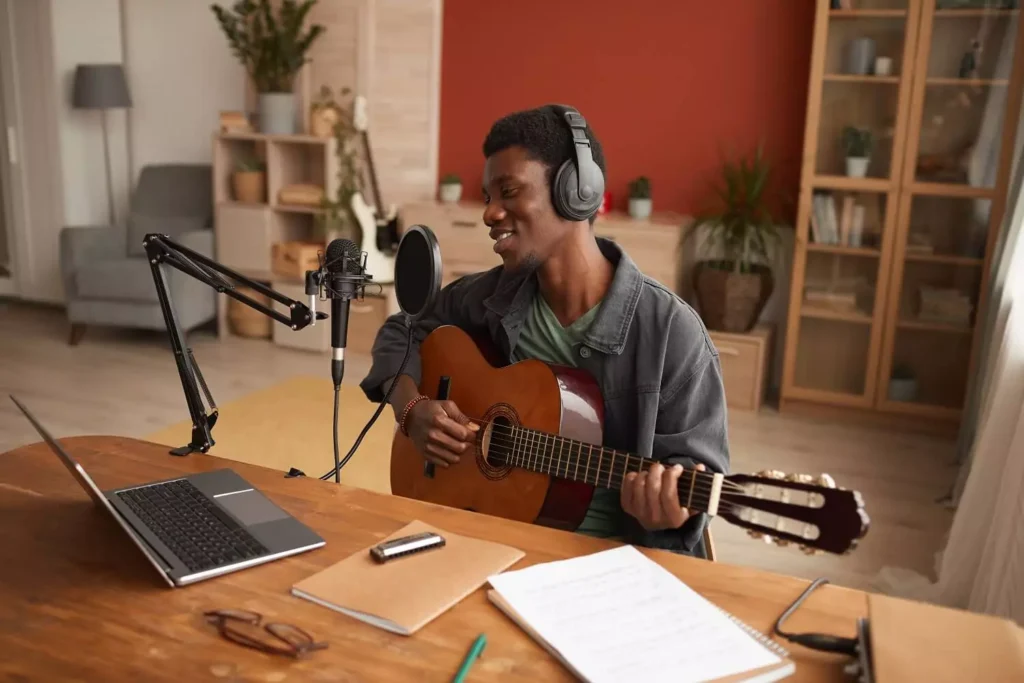 Mann spielt Gitarre bei einem Remote Live Stream aus den eigenen vier Wänden.