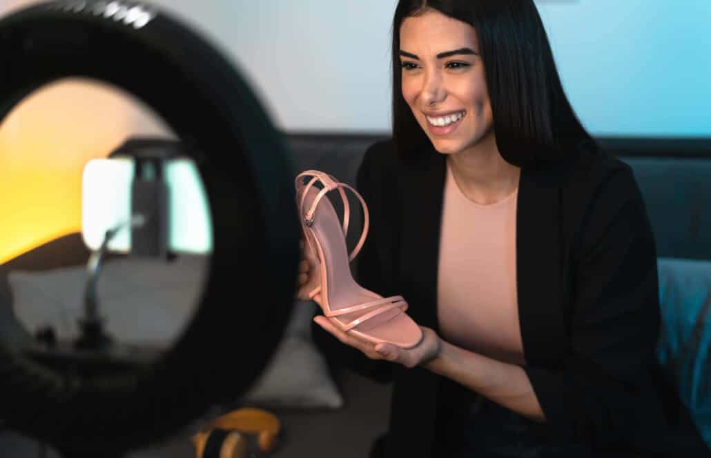 Eine Influencerin hält einen Schuh und erstellt ein eigenes Werbevideo in ihren eigenen vier Wänden