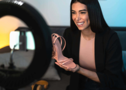 Eine Influencerin hält einen Schuh und erstellt ein eigenes Werbevideo in ihren eigenen vier Wänden