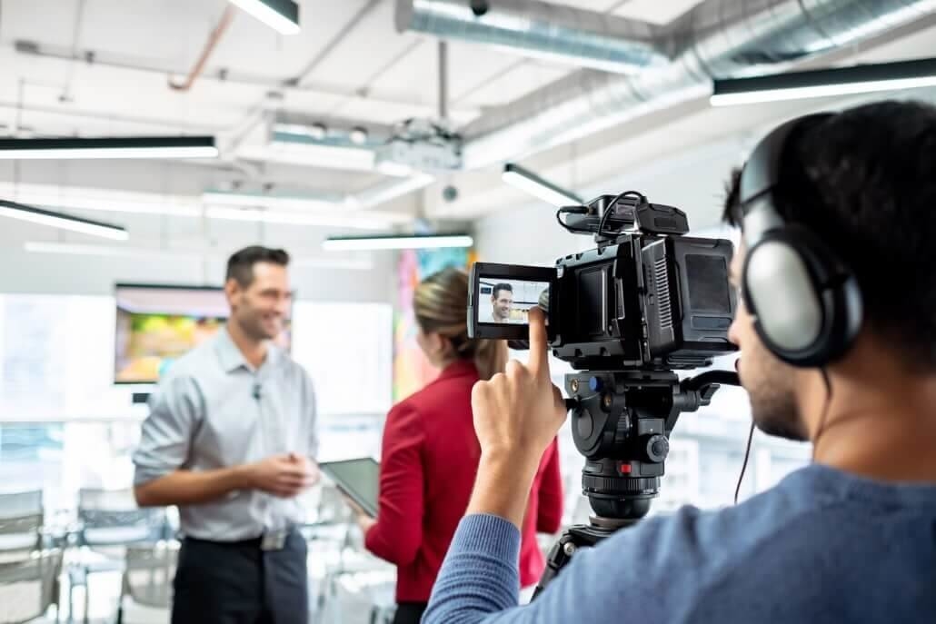 Ein Mann steht lächelnd vor einer Kamera während Werbevideo Dreharbeiten