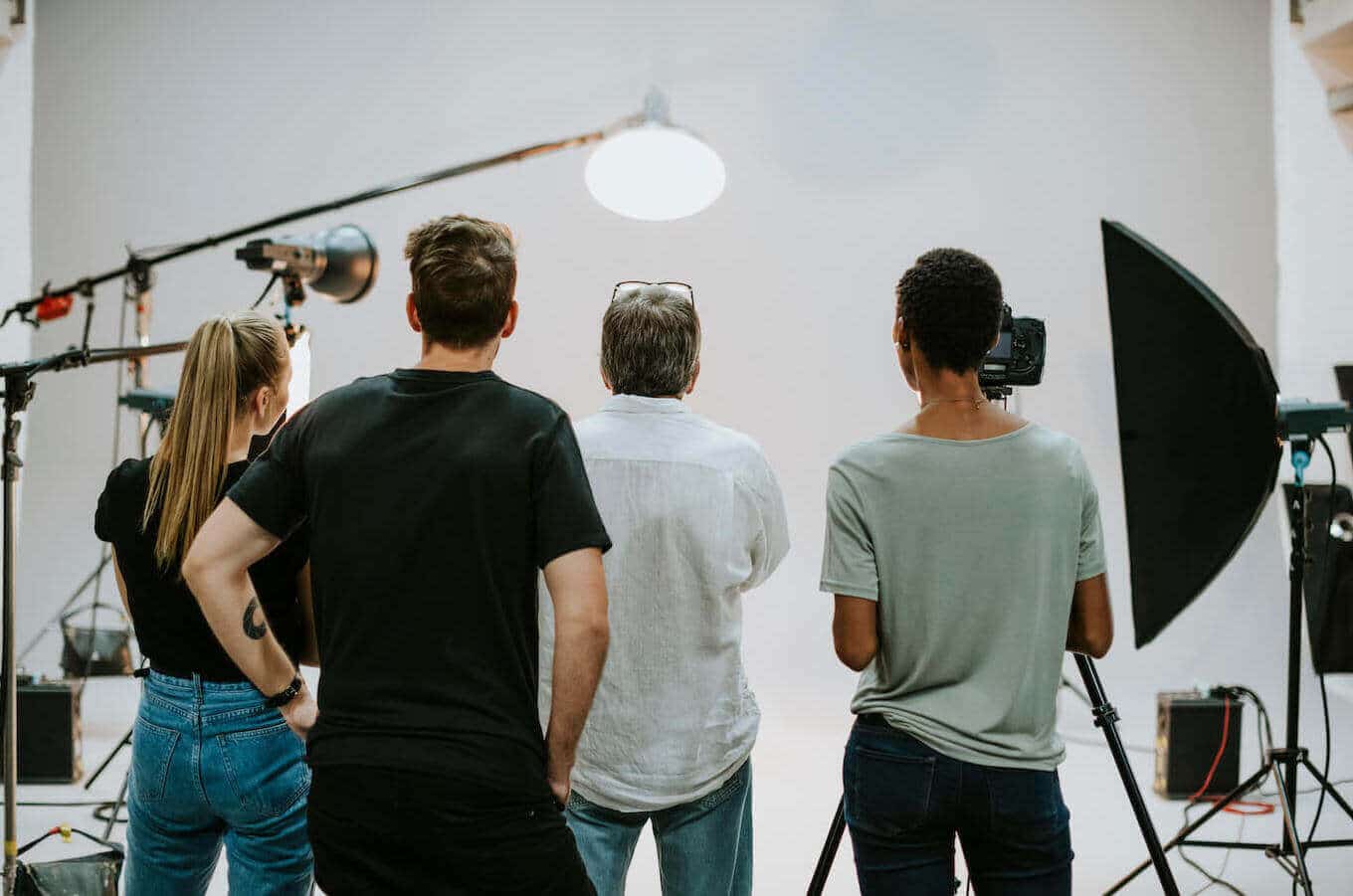 Vier Kameraleute werden von hinten bei der Arbeit in einem Studio gezeigt.