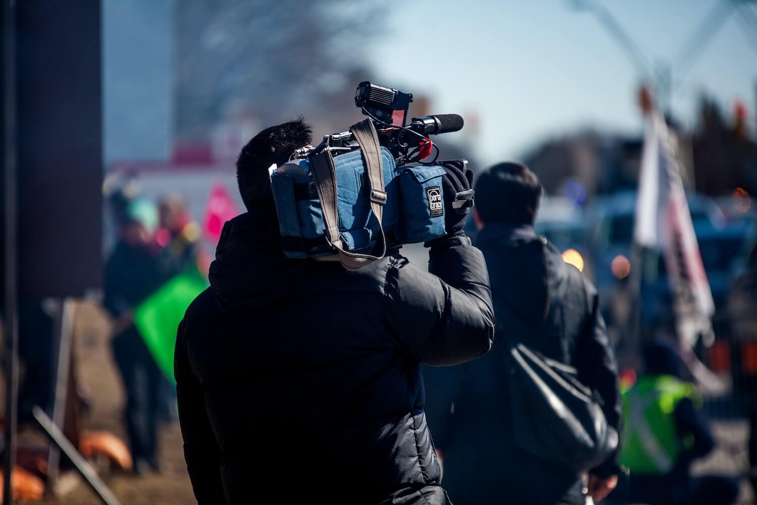 Ein Mann überträgt einen Livestream und trägt eine große Kamera auf seiner Schulter.