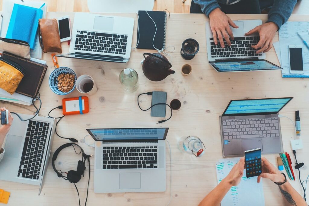 Tisch mit Laptops, iPhones und weiteren Geräten bei einem Video-/Film-Workshop von muthmedia.