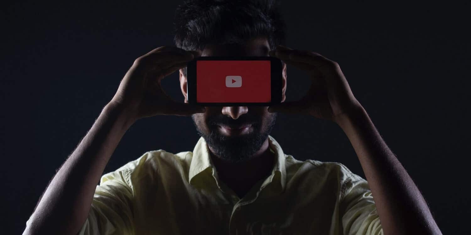 Ein Mann hält ein Smartphone mit dem YouTube-Logo vor seinem Gesicht.