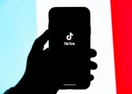 Eine Person hält ein Smartphone in der Hand, auf dem die App TikTok geöffnet wurde.