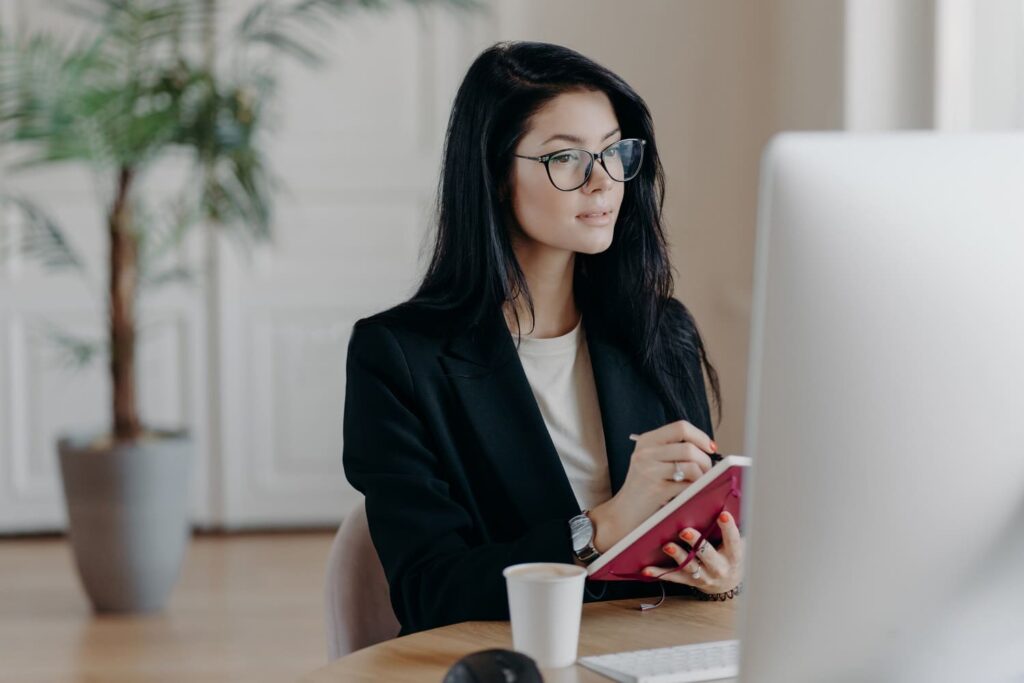 Eine neue Mitarbeiterin schaut sich ein Onboarding Video zur Wissensvermittlung an und macht sich Notizen.