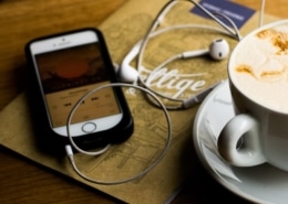 Ein Smartphone, auf dem ein gerade veröffentlichter Podcast läuft, liegt auf einem Tisch.