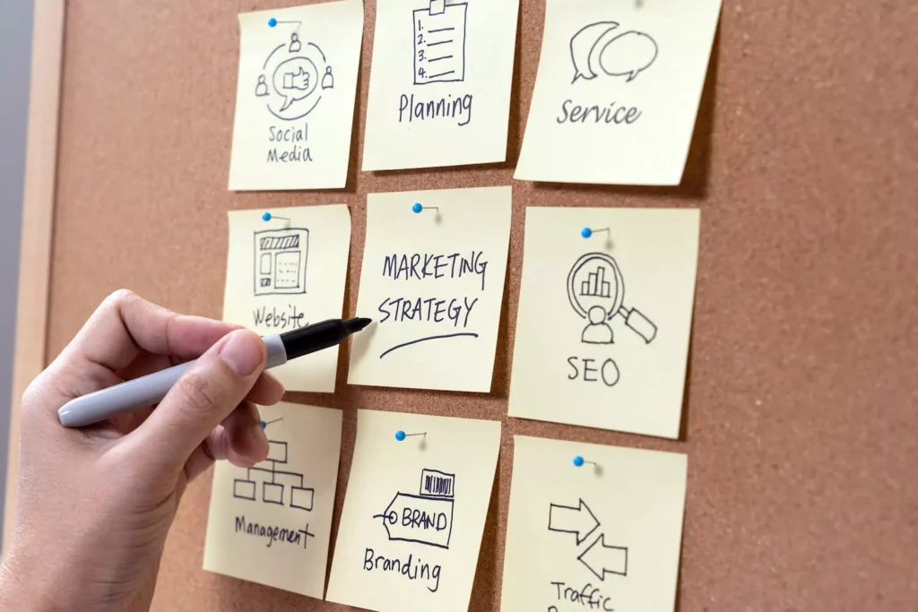 Ein Mann hält einen Stift und beschriftet Post-Its mit verschiedenen Marketingstrategien.