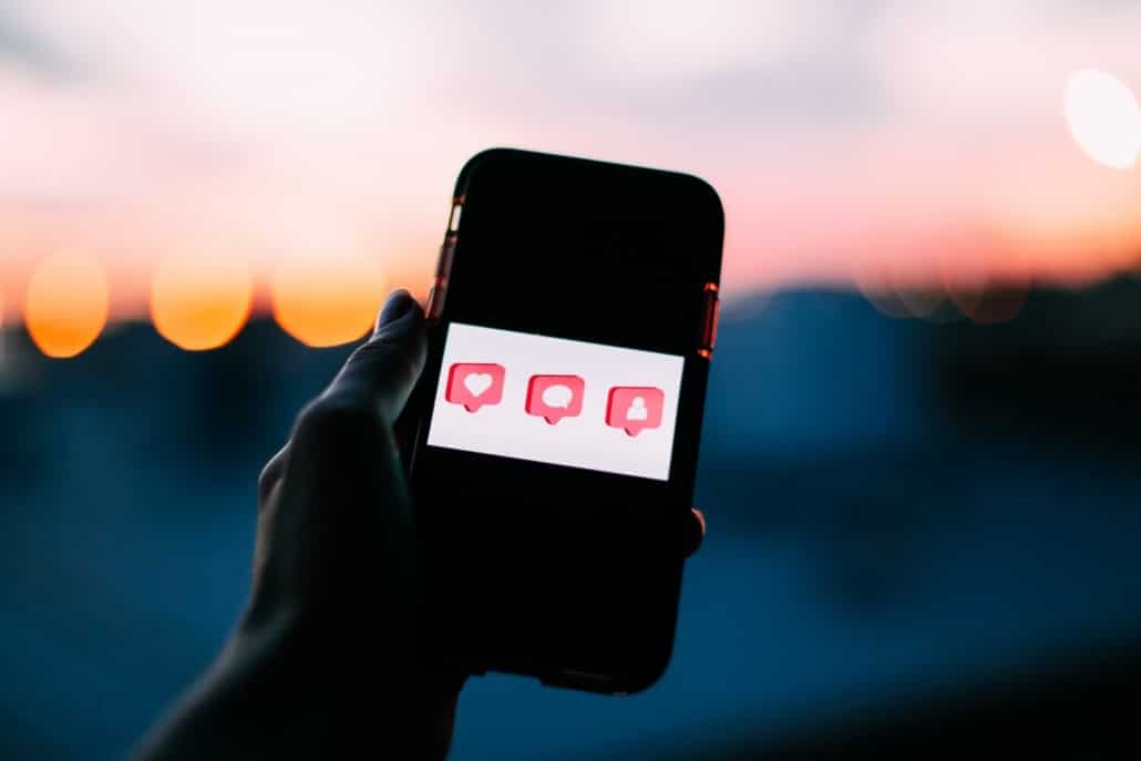 Das Display eines Smartphones zeigt die 3 Video Engagement Metriken Likes, Kommentare und Follower.