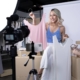 Eine Influencerin stellt ein rosafarbenes und ein weißes Oberteil vor, während sie von einer Kamera und einem Smartphone gefilmt wird.