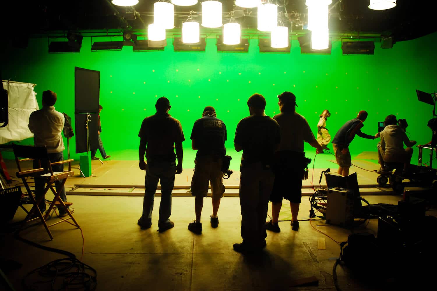 Die Mitarbeiter einer Filmagentur stehen vor einer Green Screen und produzieren einen Film.