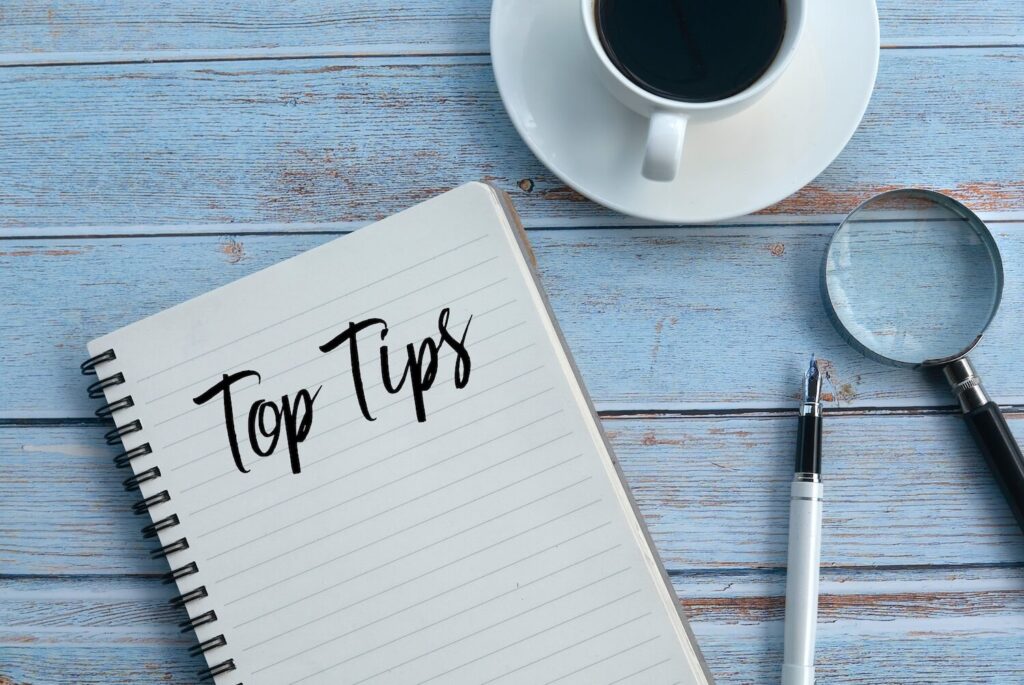 Verschiedene Gegenstände liegen auf einem Tisch neben einem Notizblock, auf dem "Top Tips" steht.
