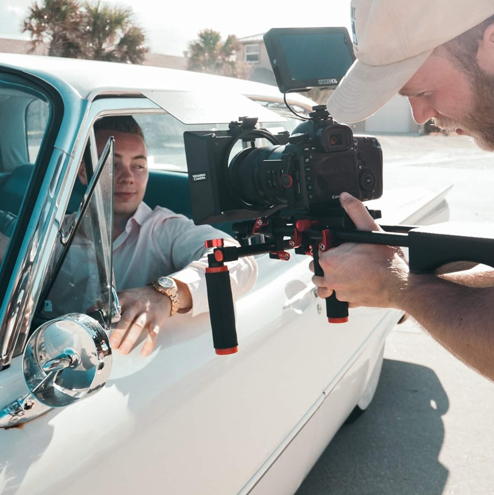 Ein Mann erstellt einen Werbespot, während er einen anderen Mann im Auto filmt.