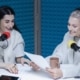 Zwei Frauen reden in Mikrofone in blauem Ton-Studio