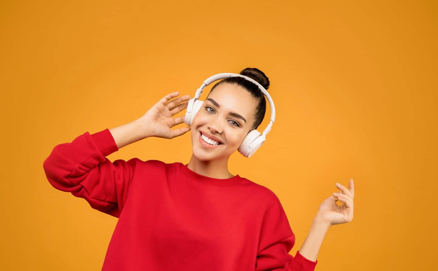 Eine junge Frau hört begeistert einen Podcast vor orangem Hintergrund
