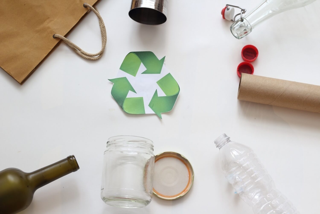 Ein grünes Recycling-Symbol, umgeben von verschiedenen Gegenständen.