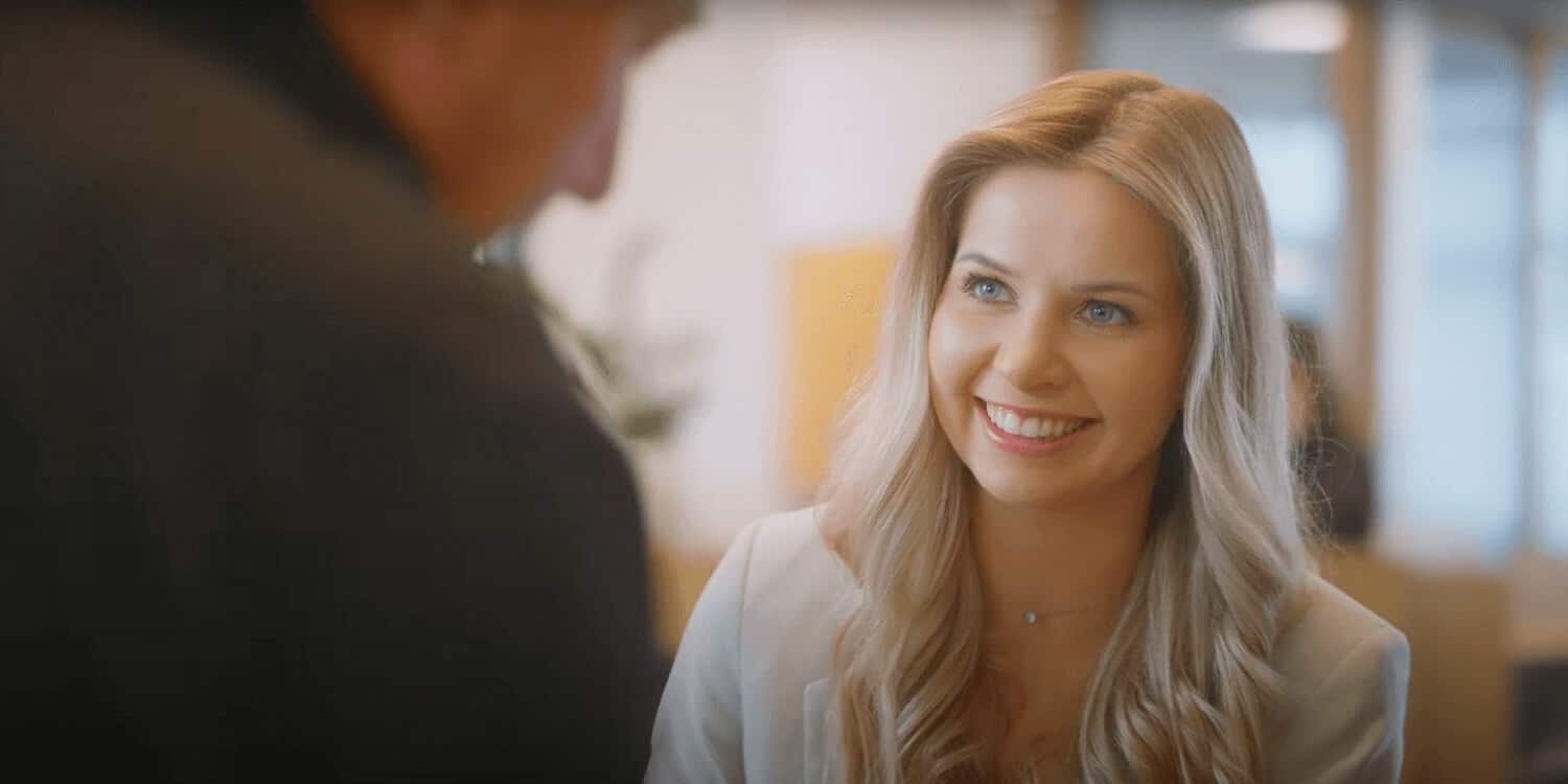 Eine lächelnde Frau in einer Szene aus einem Imagefilm für eine Bank.