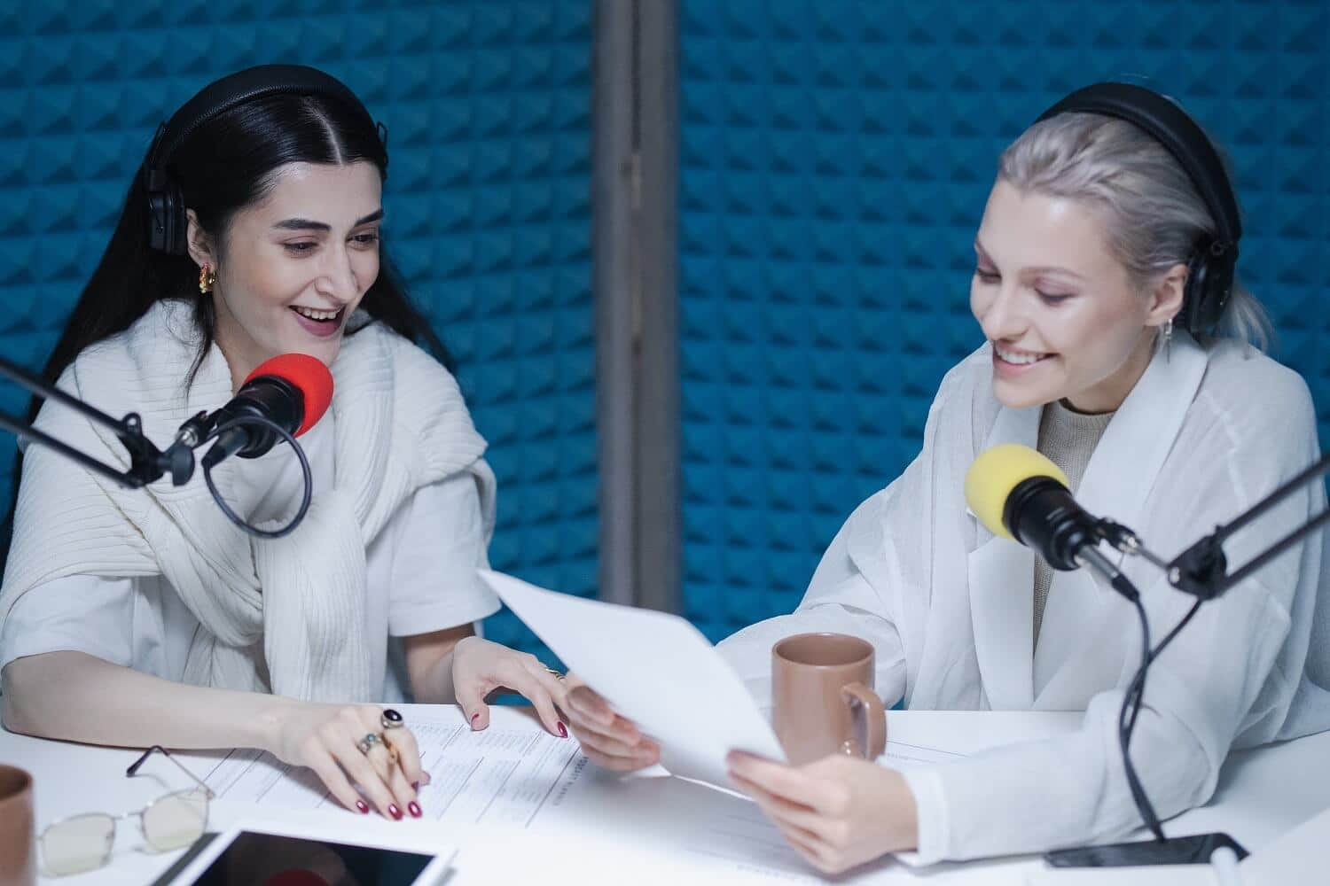 Zwei Frauen reden in Mikrofone in blauem Ton-Studio