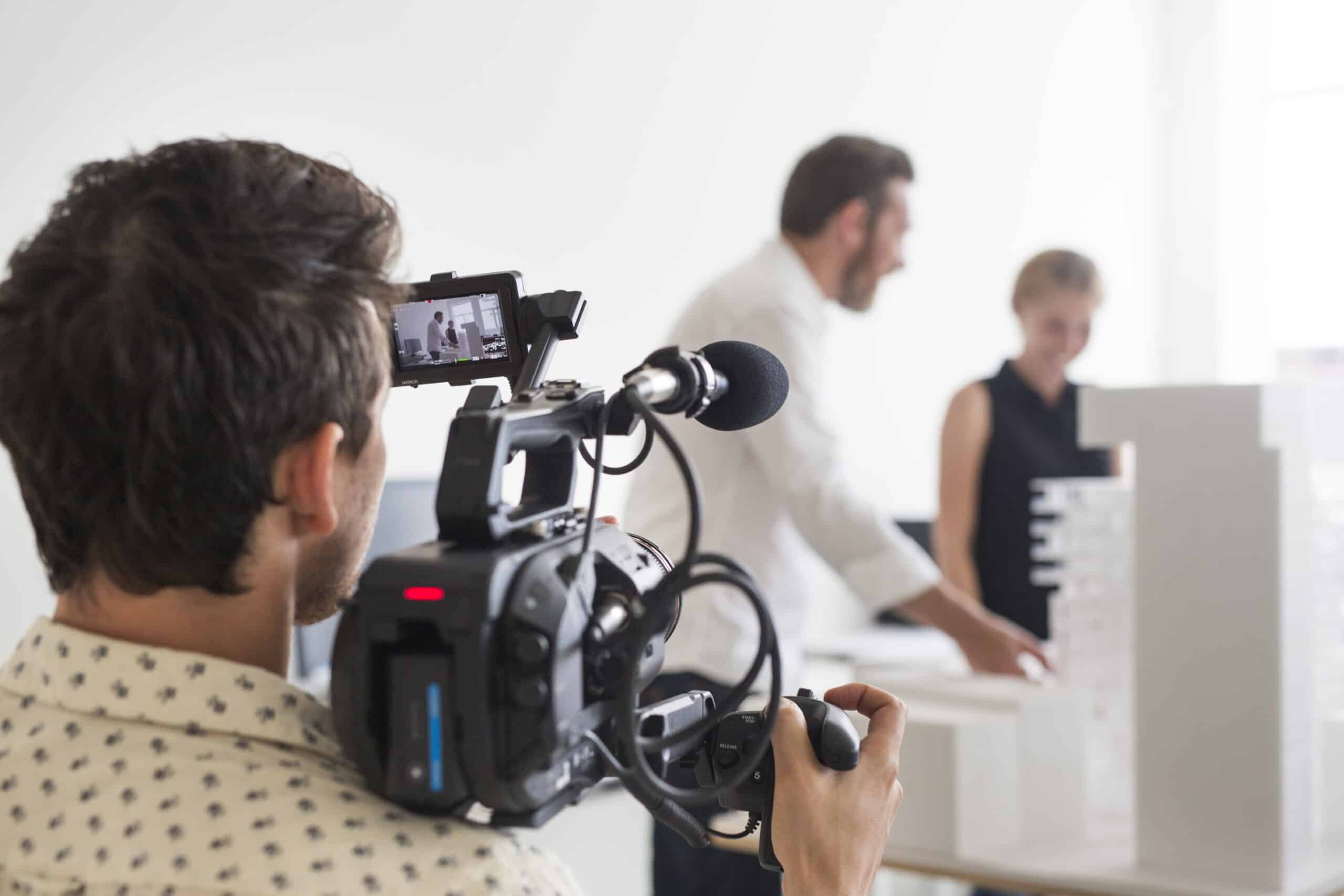 Rear view of photographer video recording business people in office