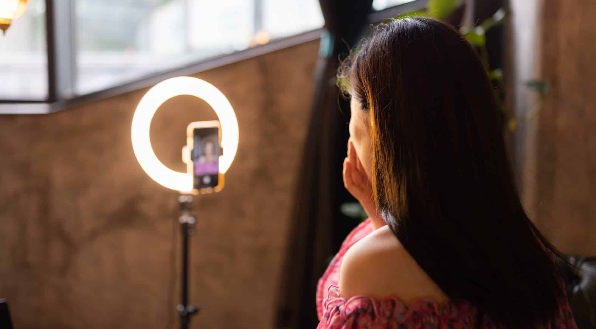 Eine Frau sitzt vor einem Smartphone und erstellt ein Instagram Video. Blogbeitrag. Titelbild.