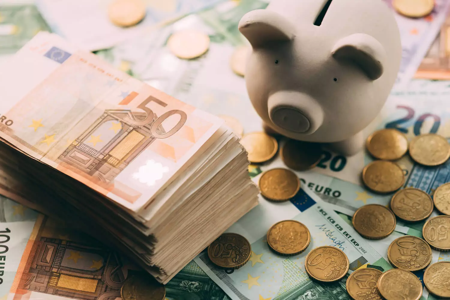 Geld und ein Sparschwein liegen auf einem Tisch.