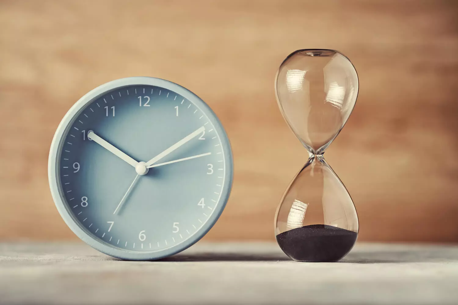 Eine Uhr und eine Sanduhr, die sich auf einem Tisch befinden.