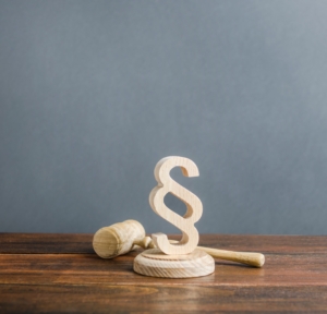 Symbol eines Paragraphen aus Holz mit Holthammer dahinter